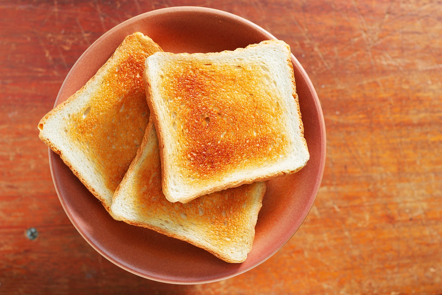 Vista superior de un plato con rodajas de pan tostado en un bowl sobre una superficie de madera